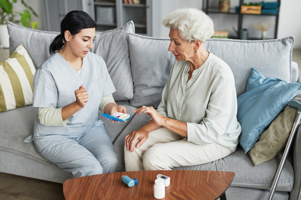 Pflegekraft unterst&uuml;tzt eine Seniorin bei der richtigen Einnahme ihrer Medikamente